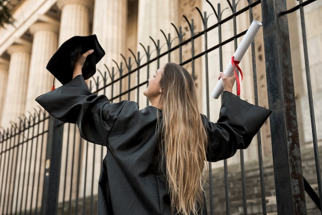 Giovane donna di angolo basso in vestito accademico