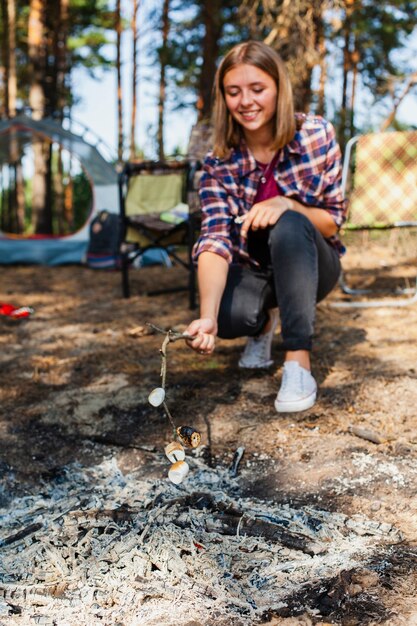 Giovane donna di angolo basso che cucina marshmellow