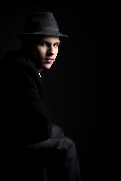 Free photo low key shot of young man in hat