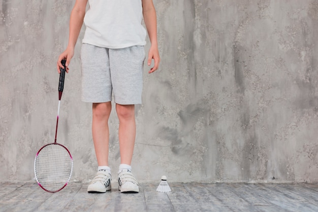 Free photo low section of a boy standing with racket and shuttlecock