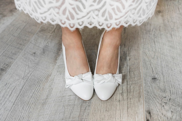 Sezione bassa della gamba della sposa che indossa scarpe eleganti bianche