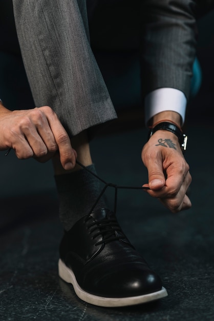 Low section of businessman's hand tying shoelace