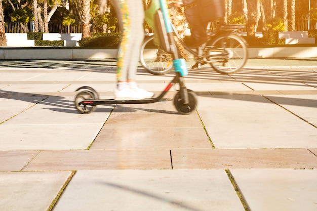 Low section of a child riding kick scooter in park