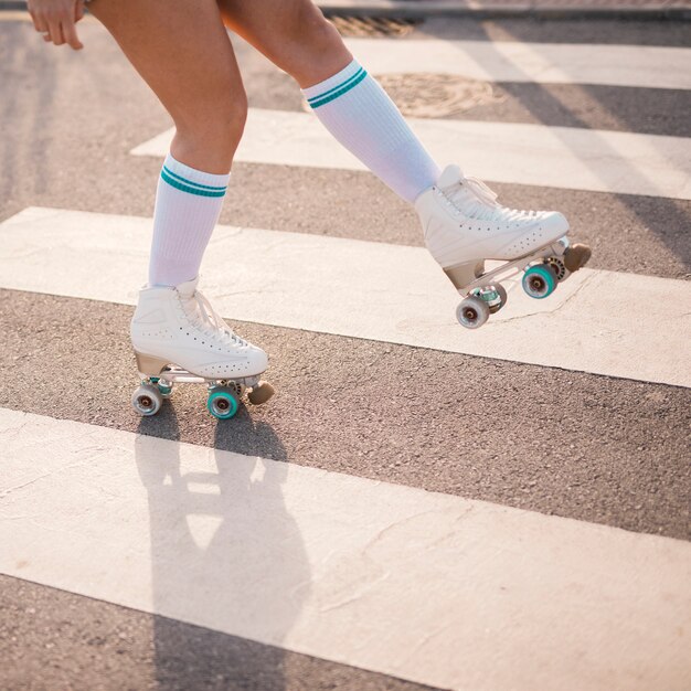 Low section of female skater skating on crosswalk
