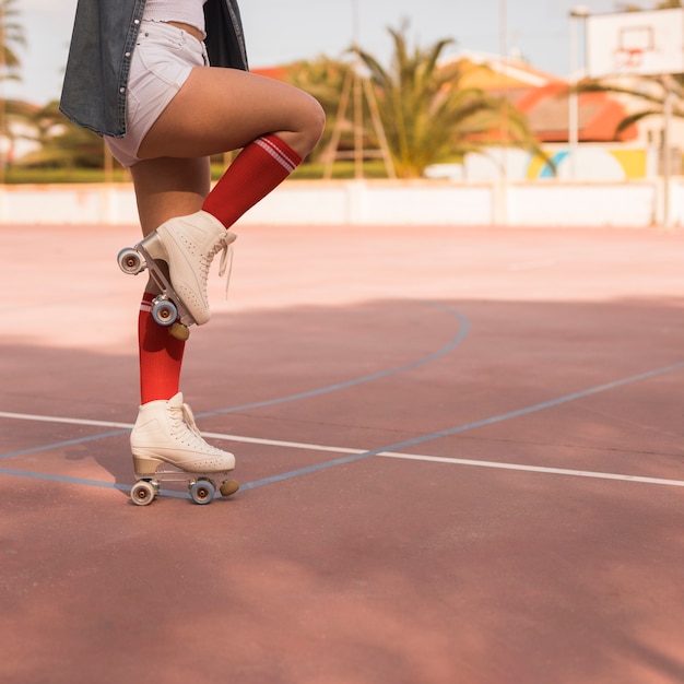 Low section of a female skater standing on one leg over the court