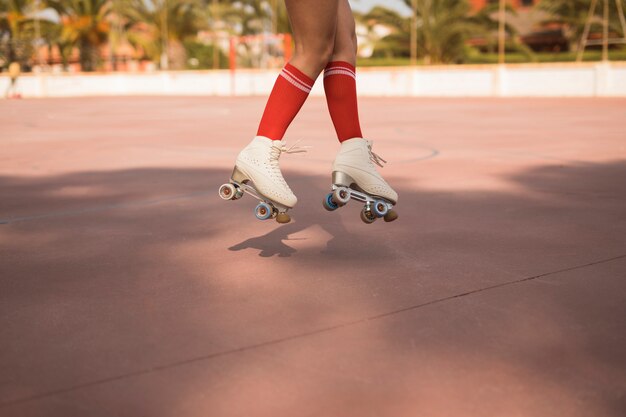 Low section of female wearing white roller skate jumping in air