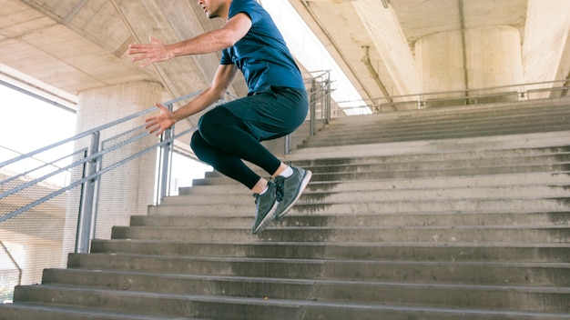 Low section of male athlete jumping on staircase