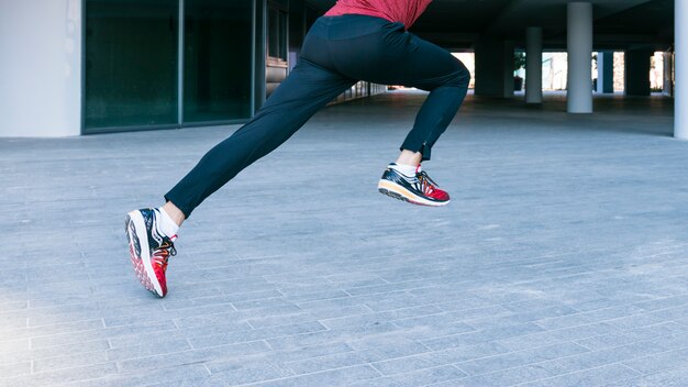 Low section of male athlete running and jumping at outdoors