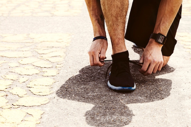 Sezione bassa di un atleta maschio che lega il laccetto