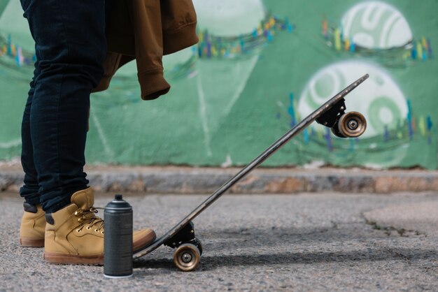 Low section of a man with skateboard and aerosol can