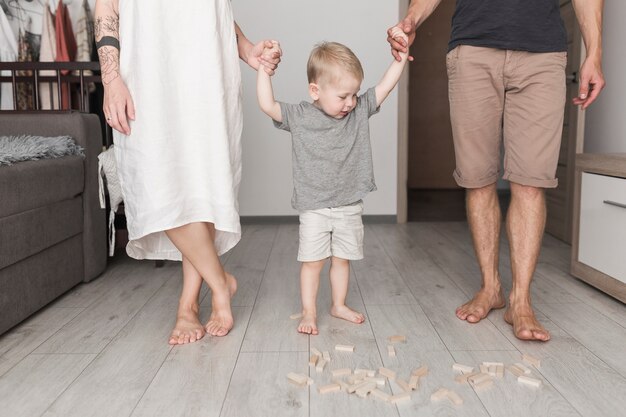 Sezione bassa del genitore che tiene la mano del figlio a casa