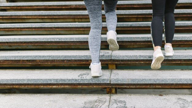 Low section of two female runner jogging on staircases