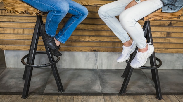 Free photo low section of two male friends sitting on bar stool in restaurant