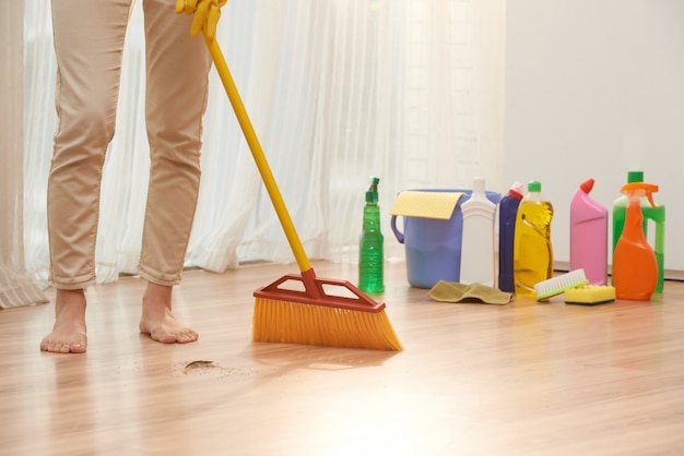 Low section of unrecognizable woman sweeping floor with broom