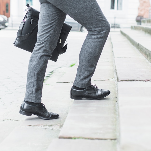 Free photo low section view of a businessman climbing staircase