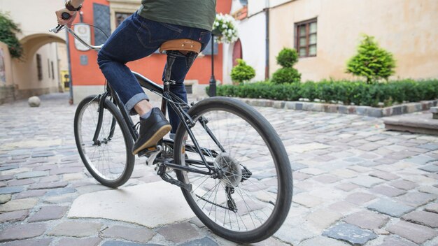 Low section view of a cyclist riding bicycle on pavement