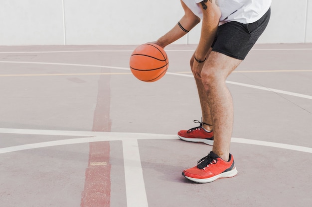 Low section view of a man practicing basketball in court