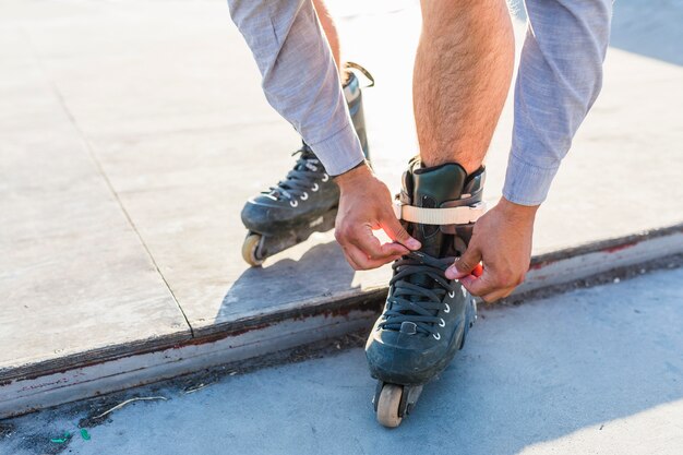 Low section view of man putting on rollerskates