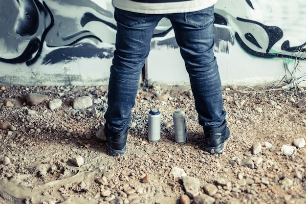 Low section view of a man's foot with aerosol cans