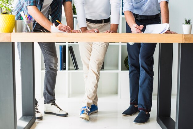 Low section view of three male architect working in office