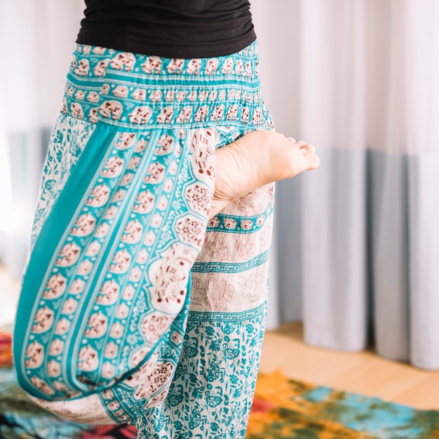 Low section of woman doing yoga practice at home