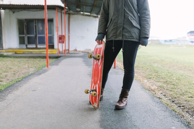 歩道にスケートボードを持っている女性の低いセクション