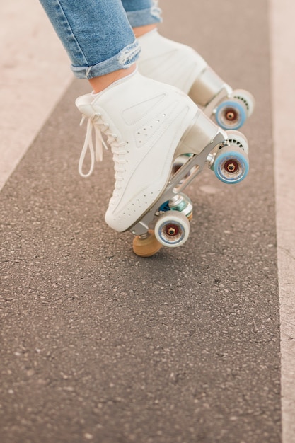 Free photo low section of woman's foot wearing white roller skate balancing on road