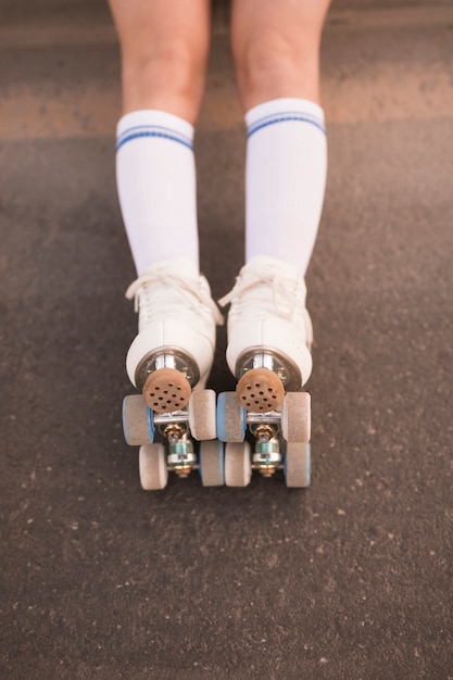 アスファルトの上のローラースケートを着て女性の足の低いセクション