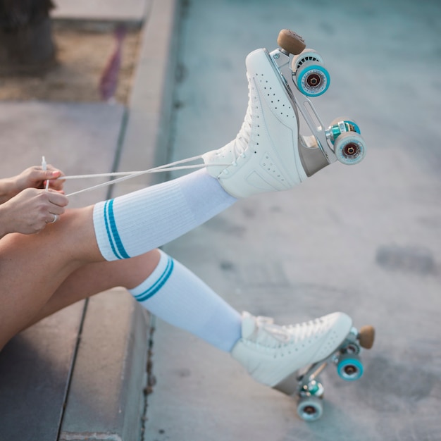 Low section of woman tying the lace of roller skate on the road