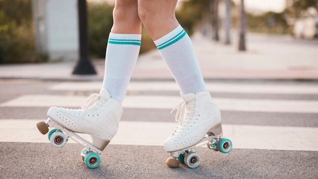 Low section of woman wearing vintage roller skate walking on road