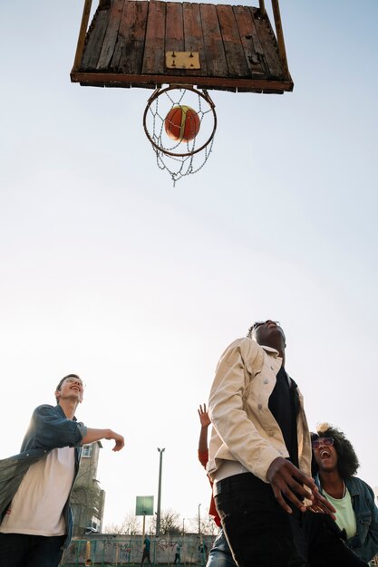 Low view group of friends playing basketball outdoors