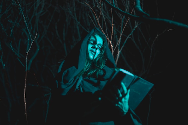 Low view man holding a lantern and a book in the night