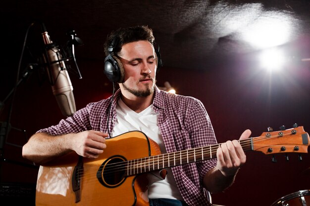 Low view shot of a man playing guitar and wearing headphones