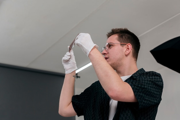 Low view of sideways man holding photo strips