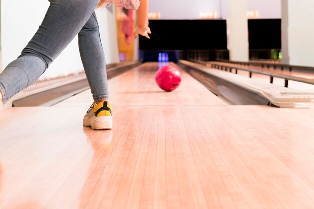 Low view woman throwing bowling ball