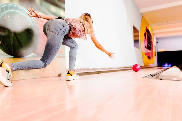 Low view woman throwing bowling ball