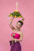 Free photo loy krathong festival. woman in thai traditional outfit holding decorated buoyant