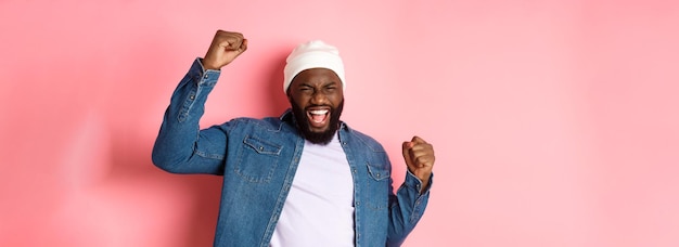 Lucky africanamerican guy winning prize raising hands up in triumph gesture scream of joy yes celebr