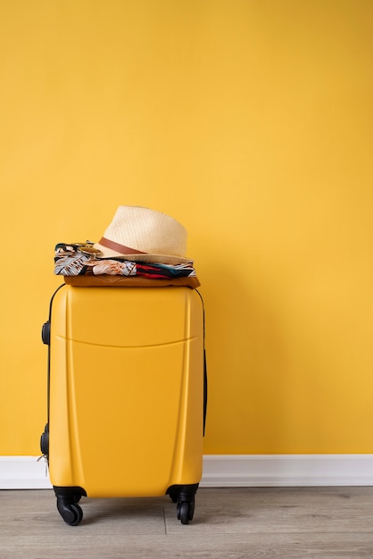 Free photo luggage with hawaiian shirts with floral print and hat