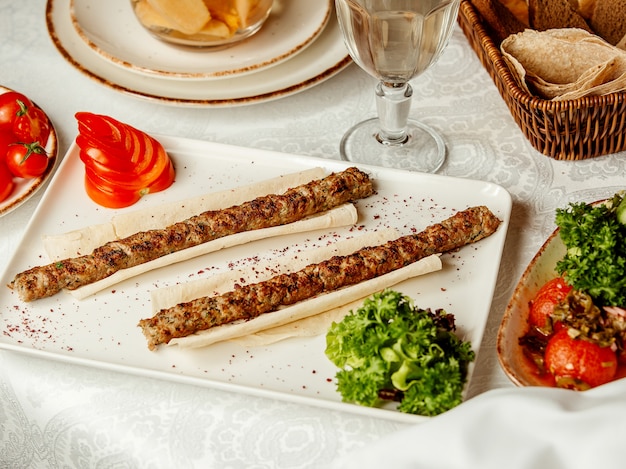 Foto gratuita kebab di lule su lavash e pomodoro affettato