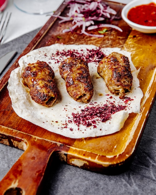 Free photo lule kebab with onions and spices on a wooden board