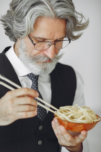 昼休み。オフィスでエレガントな男。白いシャツのビジネスマン。男は麺を食べる。