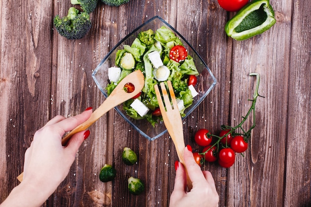 Lunch or dinner ideas. Woman shakes fresh salad of greenery, avocado, green pepper