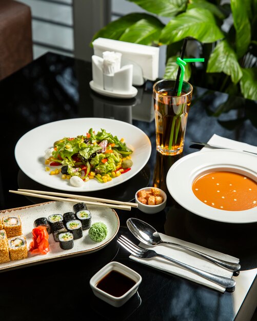 Lunch setup with lentil soup, fresh vegetables salad and sushi plate