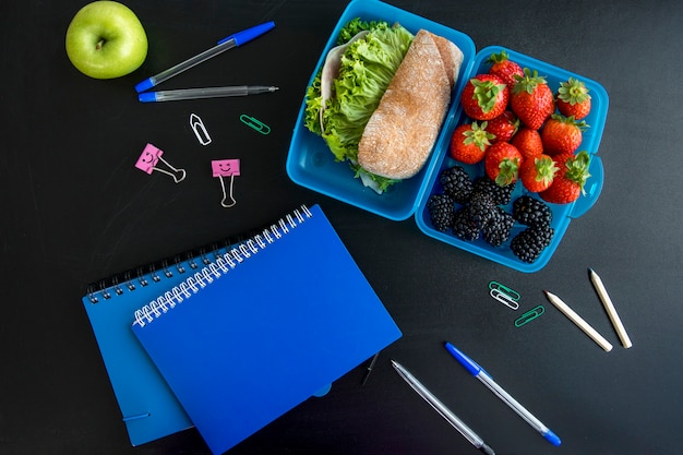 Free photo lunchbox, copybooks and stationery on table