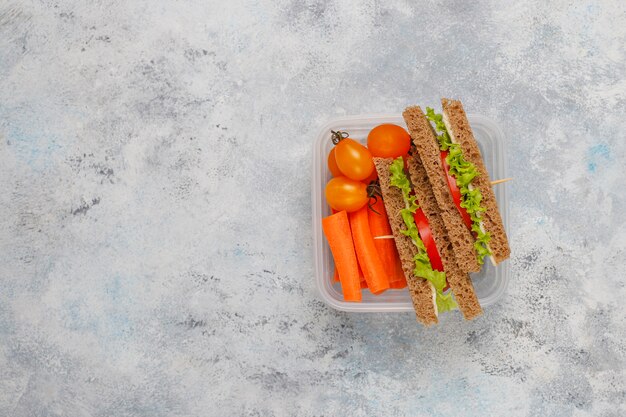 Коробка для завтрака с сандвичем, овощами, плодоовощ на белизне.