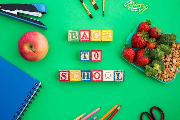 Foto gratuita lunchbox, cubetti di legno e articoli di cancelleria sul tavolo