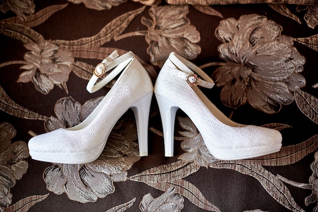 Luxurious white shoes lie on the carpet