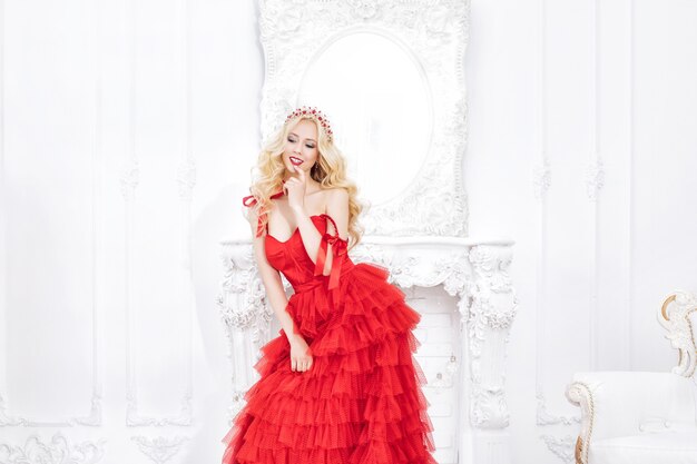 シックな​赤い​ドレス​と​インテリア​の​装飾​で​豪華な​若い​美しい​モデル​の​ブロンド​の​女性
