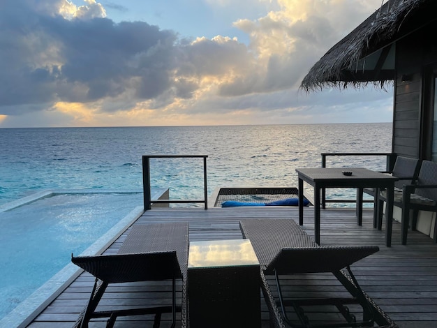 Foto gratuita bungalow di lusso vicino a una piscina senza fine sopra il mare al tramonto di un'isola tropicale d'estate